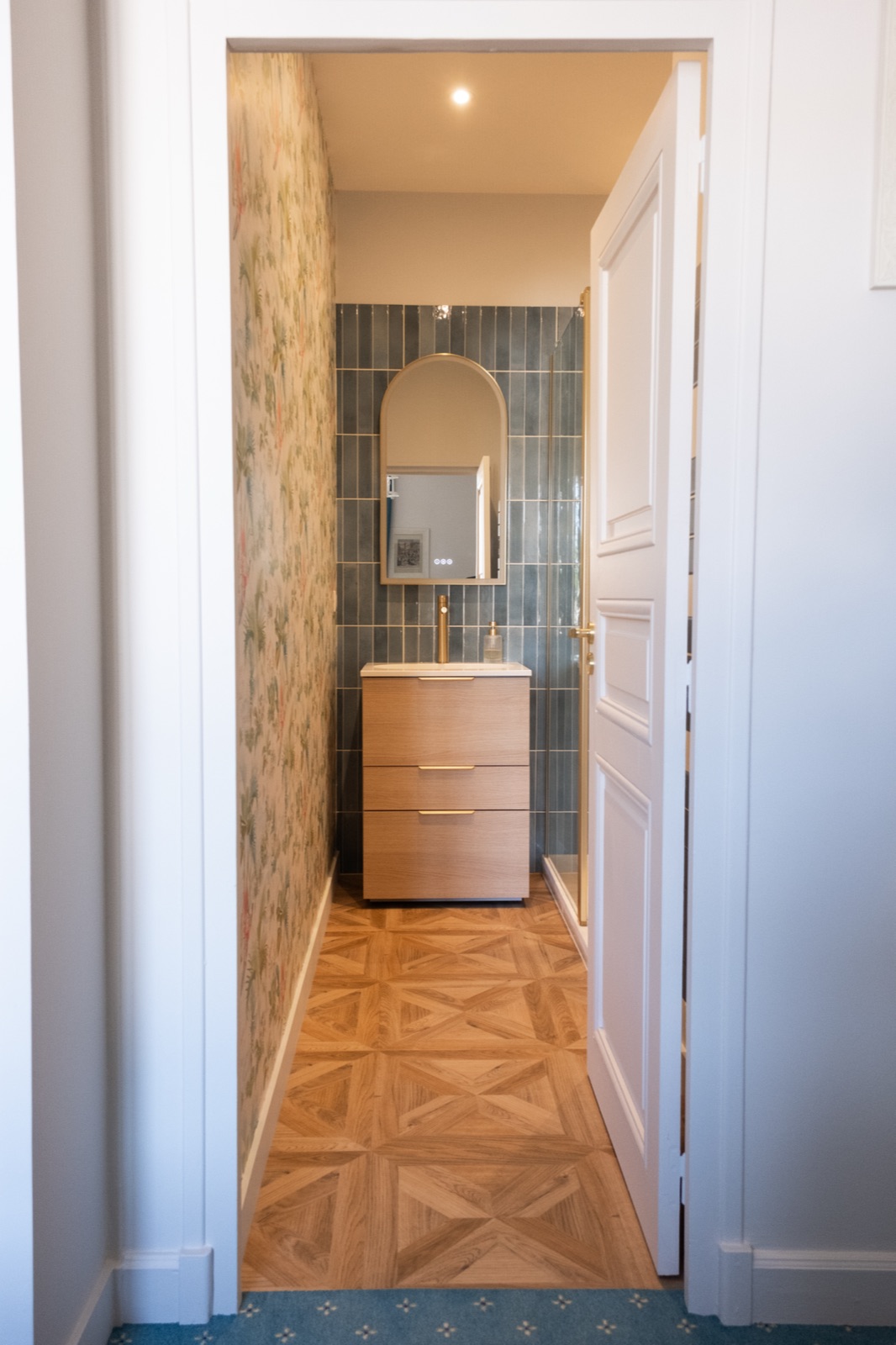 Salle de bain accessible depuis un couloir au parquet géométrique