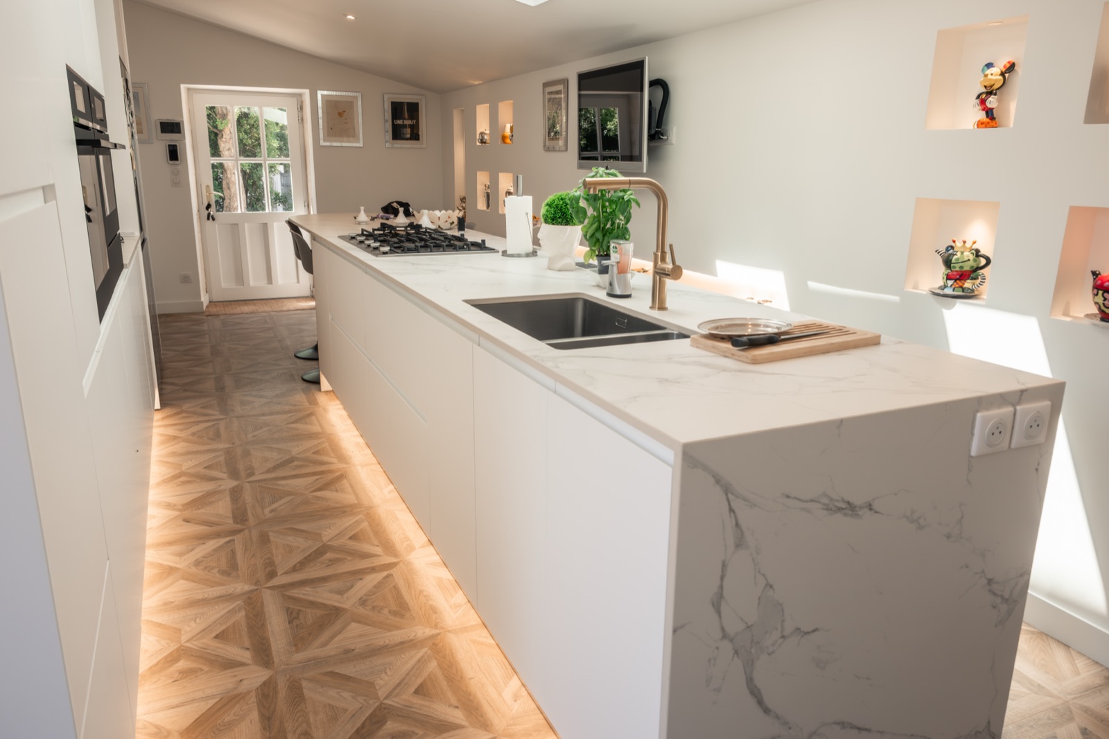 Cuisine longue, sol PVC effet parquet géométrique posé jusqu'à l'îlot marbre