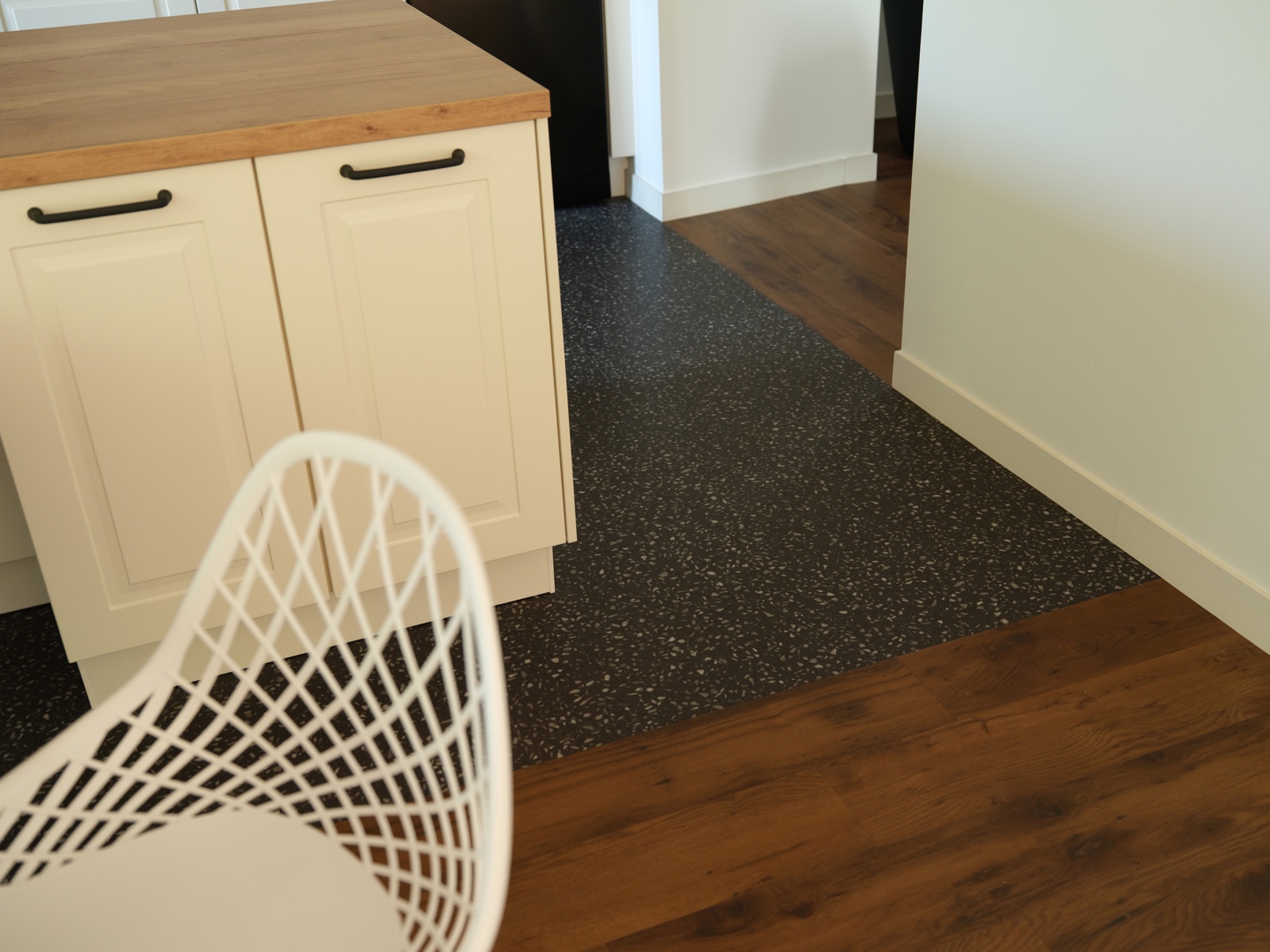 Espace cuisine marqué par un design terrazzo, en transition avec le parquet vinyle de la salle à manger