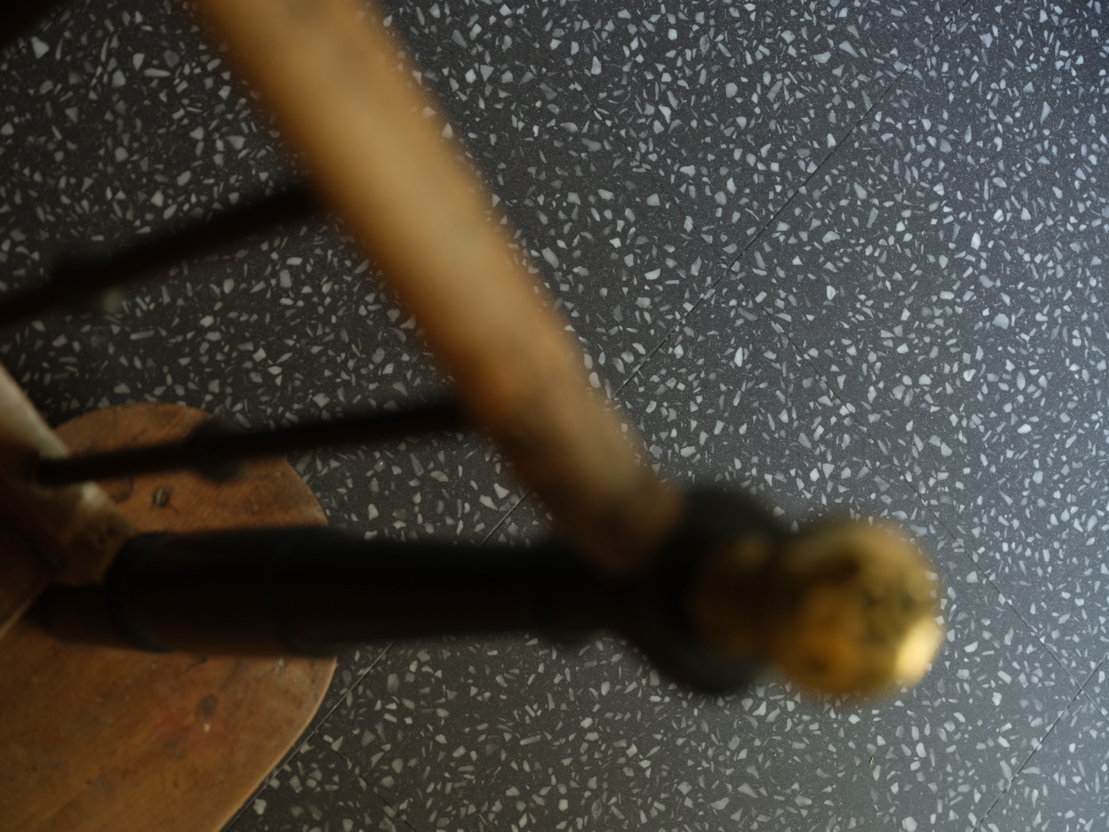Texture du terrazzo gris foncé, sous un pied de meuble ancien